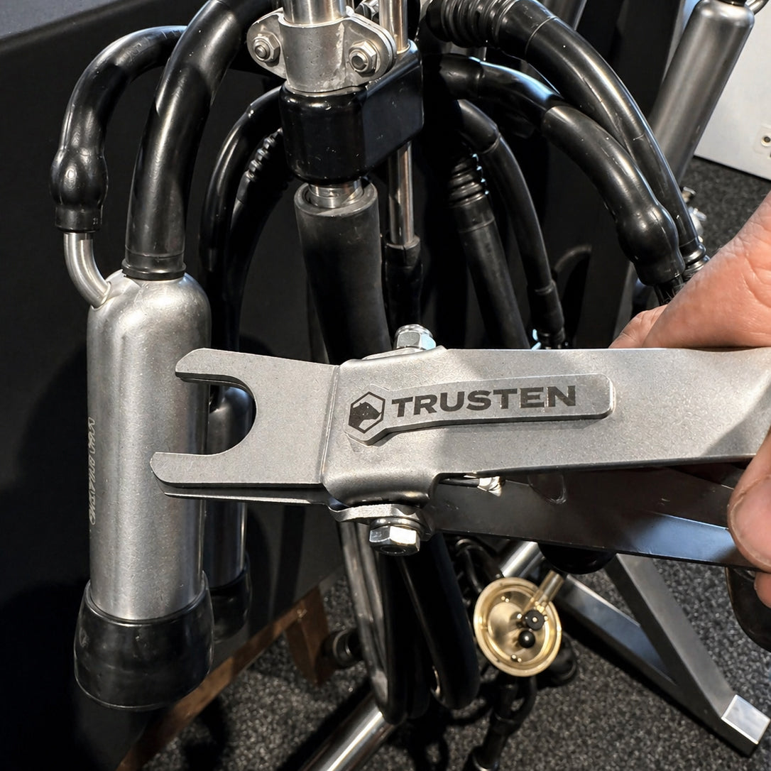Trusten milk line releaser tool being used on milking equipment in a shed.